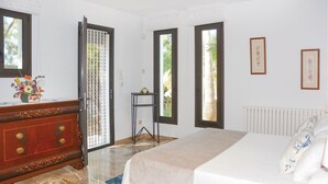 A bedroom with a bed, a dresser, a radiator, and two windows.
