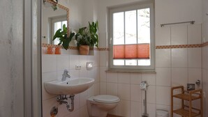 Ein Badezimmer mit Waschbecken, Toilette und einem Fenster mit Jalousien.