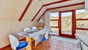 Un coin repas avec une table dressée pour quatre personnes, un ventilateur de plafond et une vue sur l’extérieur.