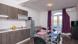 A compact kitchen with modern appliances, a dining area with a glass table, and a view through a door. - Gorgeous apartment in Dubrava with house sea view (Dubrava)