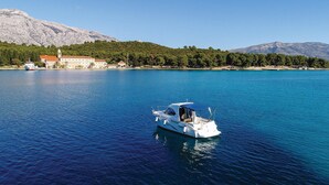 A boat on a calm sea with a coastal building in the background. - Gorgeous apartment in Dubrava with house sea view (Dubrava)