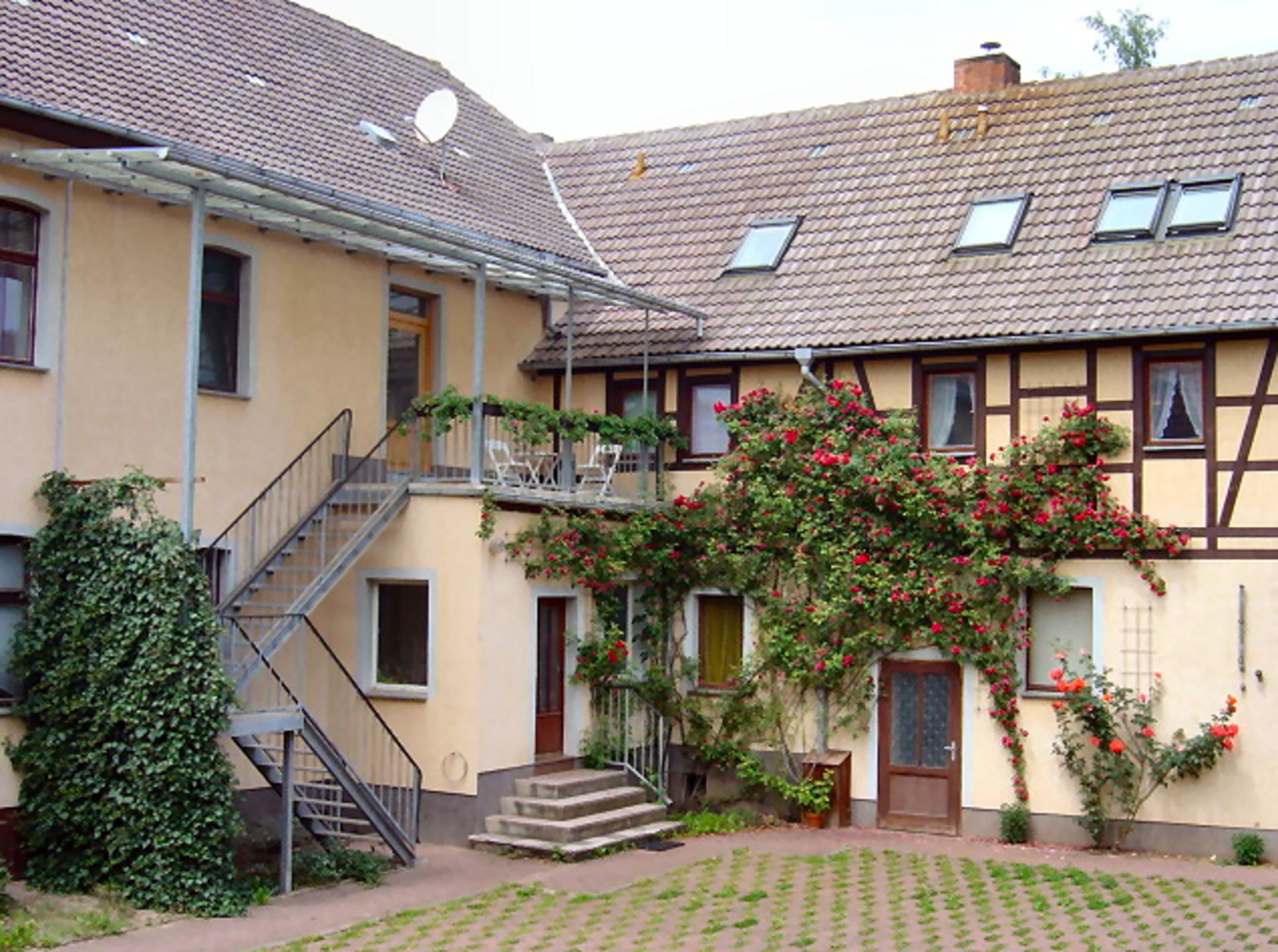 Un bâtiment à deux étages doté d’un balcon, d’un escalier et d’un espace jardin.