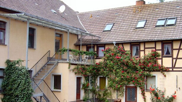 En toetagers bygning med balkon, trappe og en have.