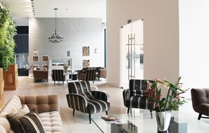 A spacious lobby with a high ceiling, a chandelier, and a seating area with striped chairs and sofas. - Amazing apartment in Binz with outdoor swimming pool (Prora/Rügen)
