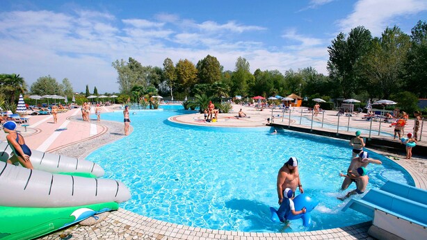 A swimming pool with inflatable slides and lounge areas. - Happy Camp in Camping Laguna Village (Caorle)