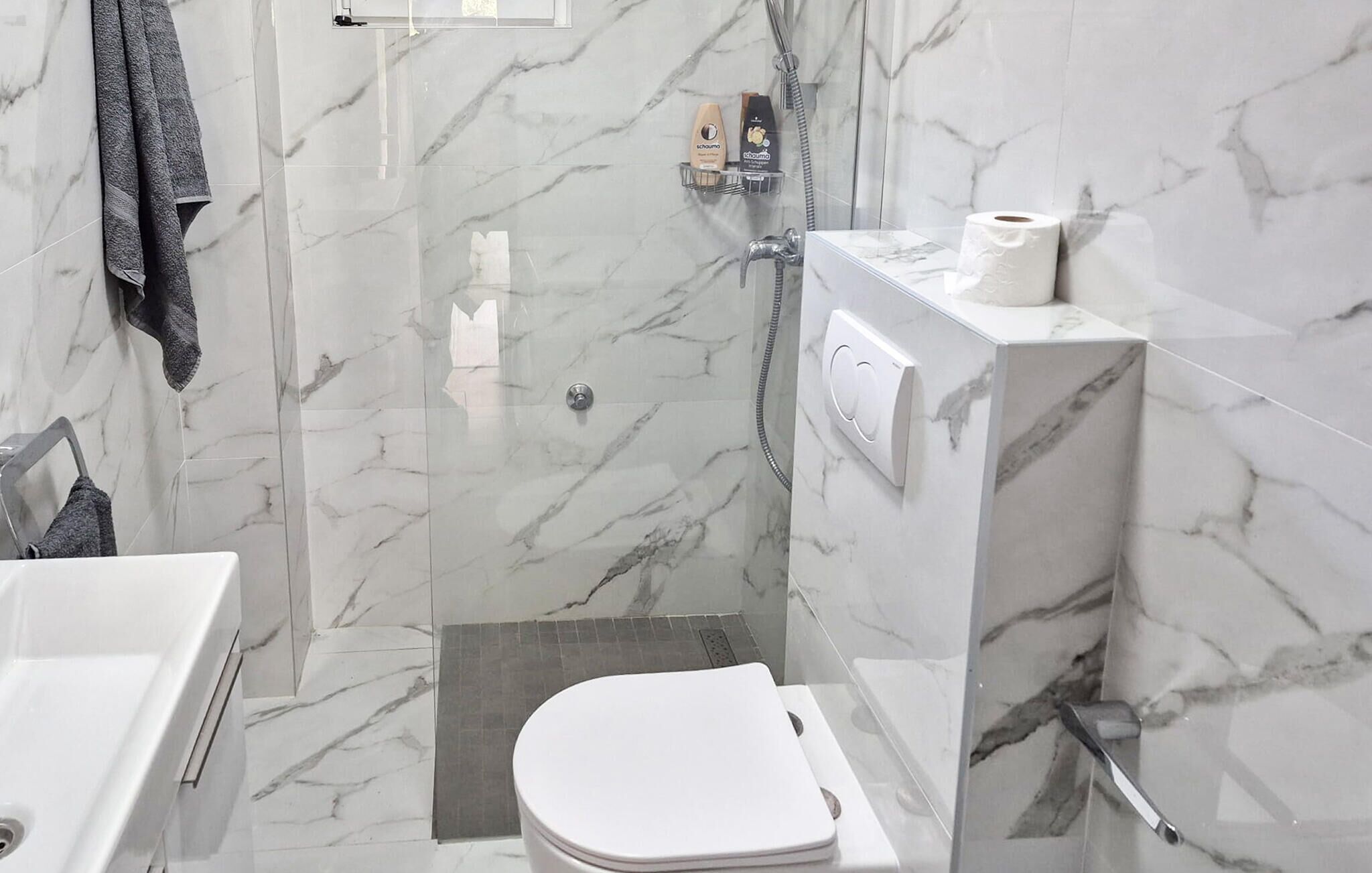 A modern bathroom with a shower, toilet, and sink.