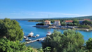 Eine Küstenstadt mit einem Yachthafen, Häusern mit roten Dächern und vor Anker liegenden Booten.