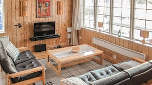 Una sala de estar acogedora con televisor, muebles de madera y un ventanal con vistas.