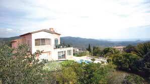 Une maison moderne avec une piscine, entourée d’une végétation luxuriante et avec des montagnes en toile de fond.