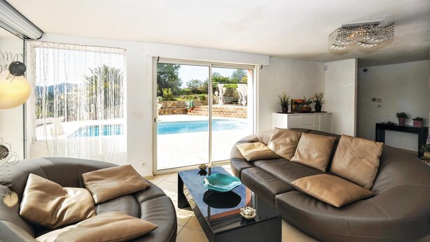 Un salon avec un canapé, une table basse et une vue sur une piscine.
