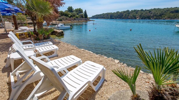 Vista al lago con sillones blancos y una sombrilla azul.