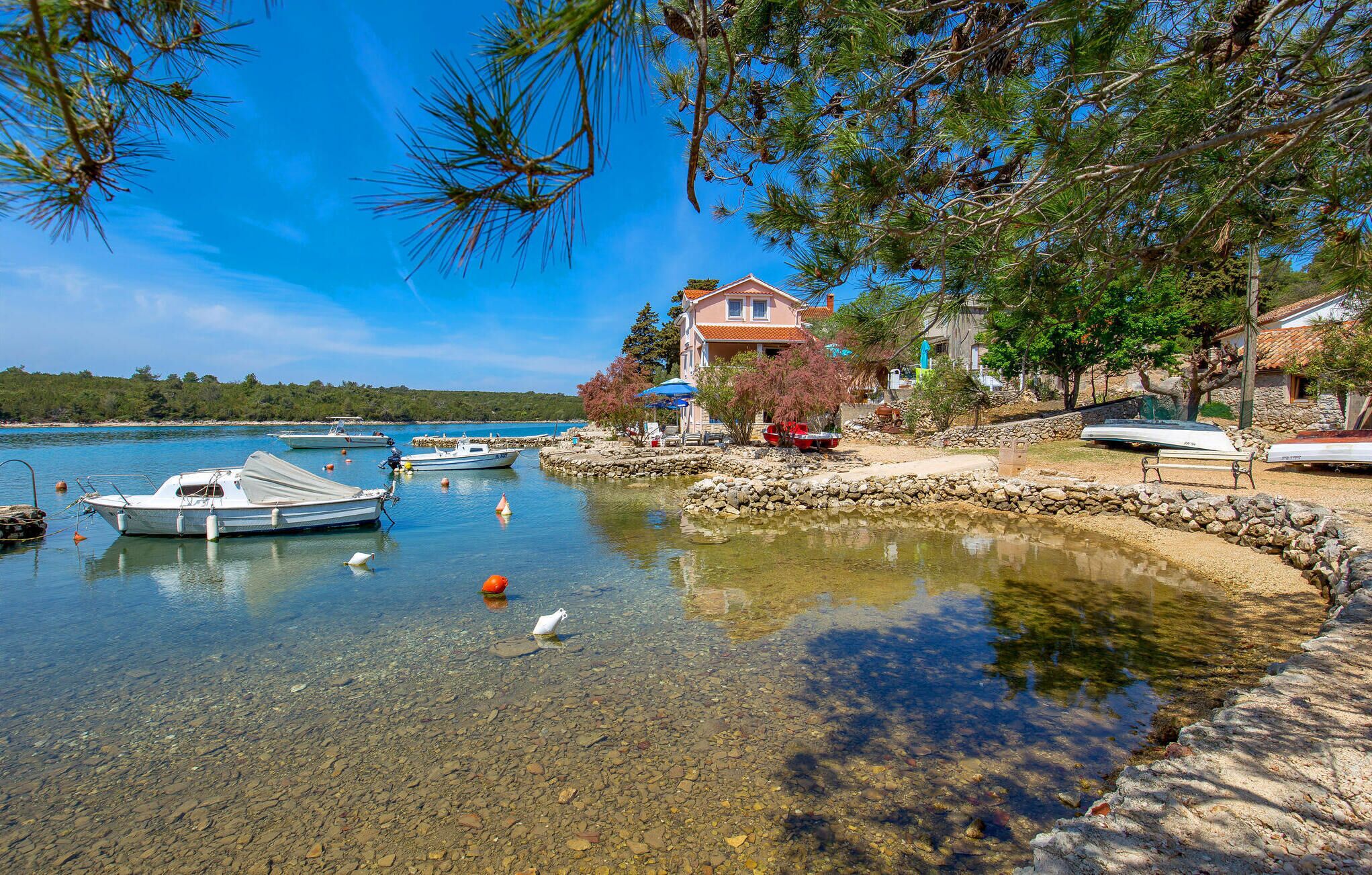 A coastal scene with boats docked near a house by the water.