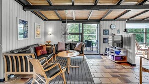 Ein gemütliches Wohnzimmer mit Sofa, Sesseln, einem Fernseher und einem Essbereich mit Tisch und Stühlen.