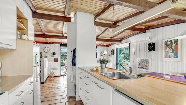 Eine moderne Küche mit weißen Schränken, einer Holz Arbeitsplatte und einem sichtbaren Geschirrspüler.