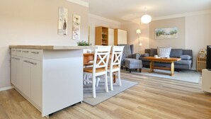 Un espacio habitable compacto con kitchenette, comedor y zona de estar.