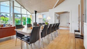 Un comedor amplio con una mesa larga, sillas negras y lámparas colgantes.