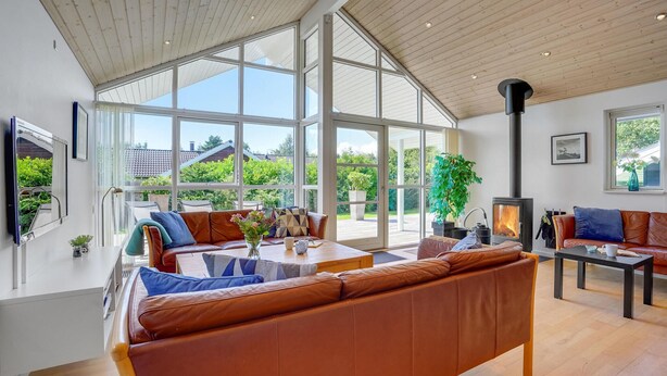 Un salón amplio con un gran ventanal, una chimenea y asientos cómodos.