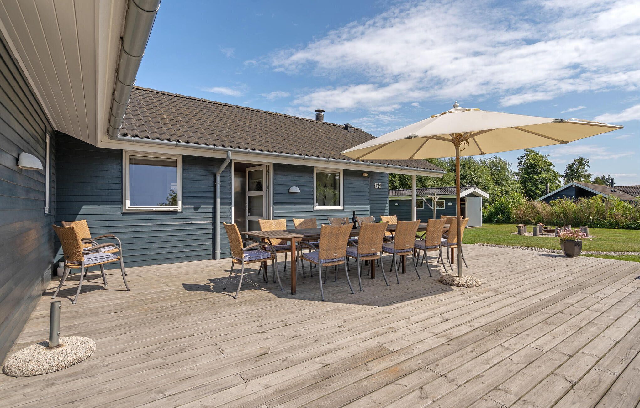 Une terrasse en bois avec des meubles d’extérieur et un grand parasol.