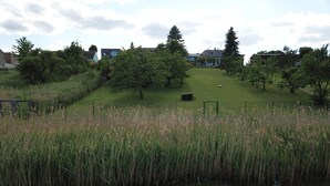 A serene park with a pond, grassy areas, and trees. - designed by Mark Pohl - winner of "Best of Interior" Award 2017 (Friedrichswalde)