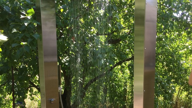 A modern, metallic water feature with a rectangular base, surrounded by lush greenery and a well-maintained garden. - designed by Mark Pohl - winner of "Best of Interior" Award 2017 (Friedrichswalde)