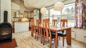 Eine moderne Küche mit einer zentralen Kochinsel, einem Holzespeisetisch mit Stühlen und einem Kamin.