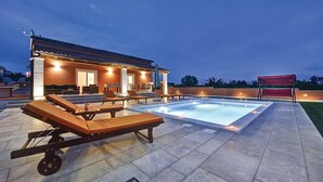 A rooftop pool area with lounge chairs, a covered seating area, and a building with a tiled roof. - Pet friendly home in Skatari (Skatari)