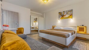 A modern hotel room with a large bed, a sofa, a desk, and a mirror. - Pet friendly home in Skatari (Skatari)