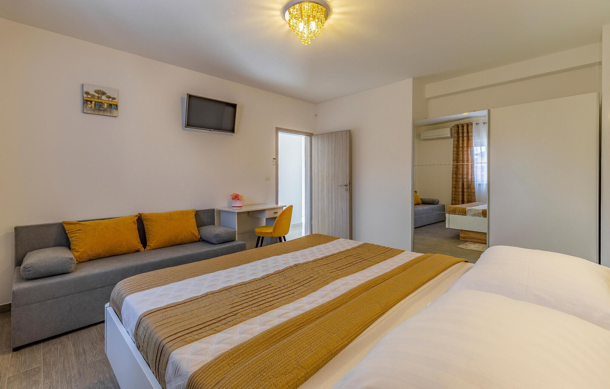 A hotel room with a bed, a sofa, a desk, and a television.
