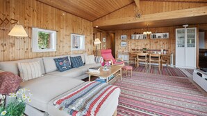 Un interior de madera acogedor con un sofá, una mesa de comedor y una zona de cocina.