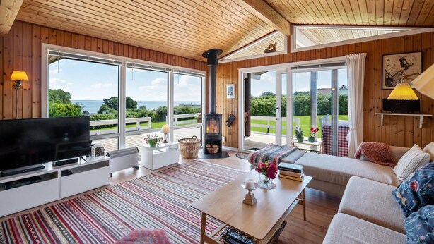 Una sala de estar acogedora con televisor grande, techo de madera y chimenea.