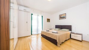 A bedroom with a bed, bedside tables, a nightstand, a painting, and a wardrobe. - Amazing apartment in Privlaka with WiFi (Privlaka)