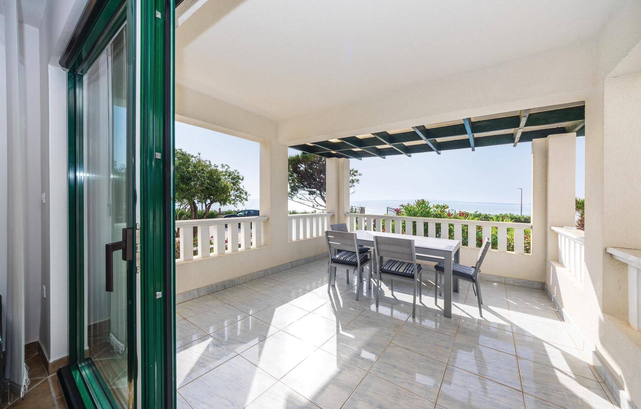 Ein Balkon mit Tisch und Stühlen, Blick auf das Meer und ein gefliester Boden.