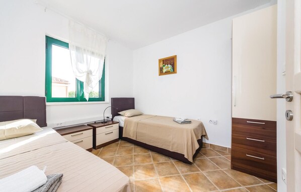 A bedroom with a bed, bedside table, lamp, and a small painting on the wall.