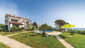 A two-story house with a swimming pool, a yellow umbrella, and a stone pathway. - Amazing apartment in Privlaka with WiFi (Privlaka)