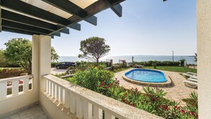 A pool area with a view of the sea, surrounded by greenery and a car parked nearby. - Amazing apartment in Privlaka with WiFi (Privlaka)