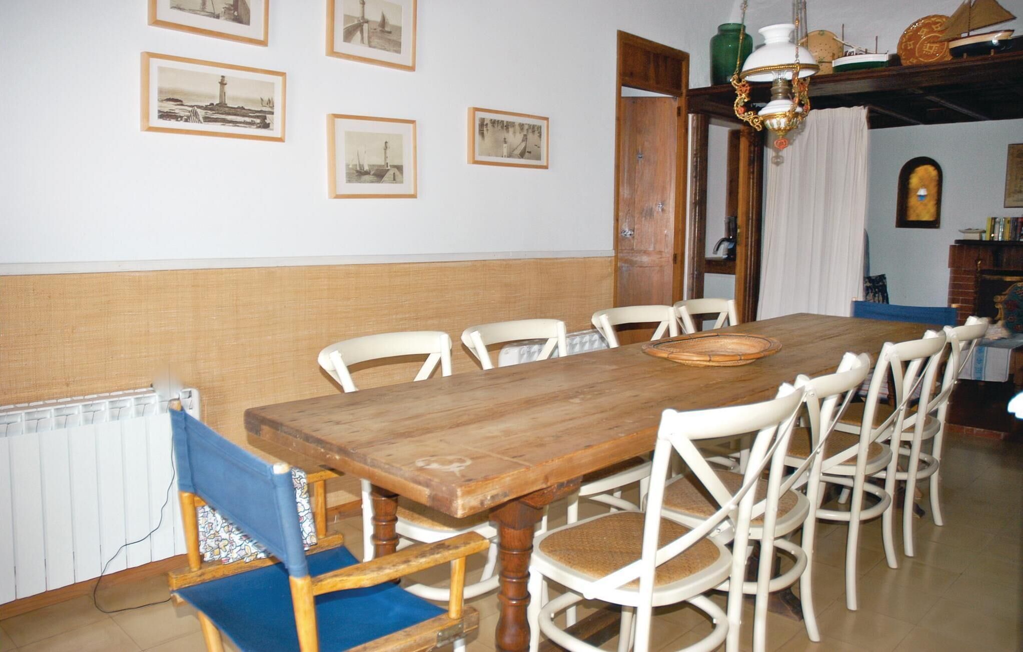 A dining room with a wooden table and white chairs, framed pictures on the wall, and a chandelier.