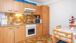 A compact kitchen with wooden cabinets, a built-in oven, a microwave, and a coffee maker. - Beach front apartment in Lucija with WiFi (Lucija)