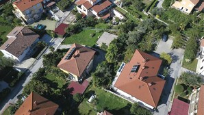 An aerial view of a residential area with houses featuring red-tiled roofs, surrounded by greenery and a well-maintained road. - Beach front apartment in Lucija with WiFi (Lucija)