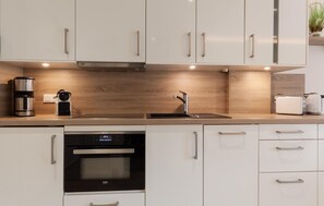Une cuisine moderne dotée d’appareils électroménagers en acier inoxydable, d’un four encastré et d’un pare-feu en bois.
