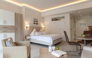A hotel room with a bed, bedside table, chair, and a small dining area. - Beach front apartment in Binz with WiFi (Prora/Rügen)