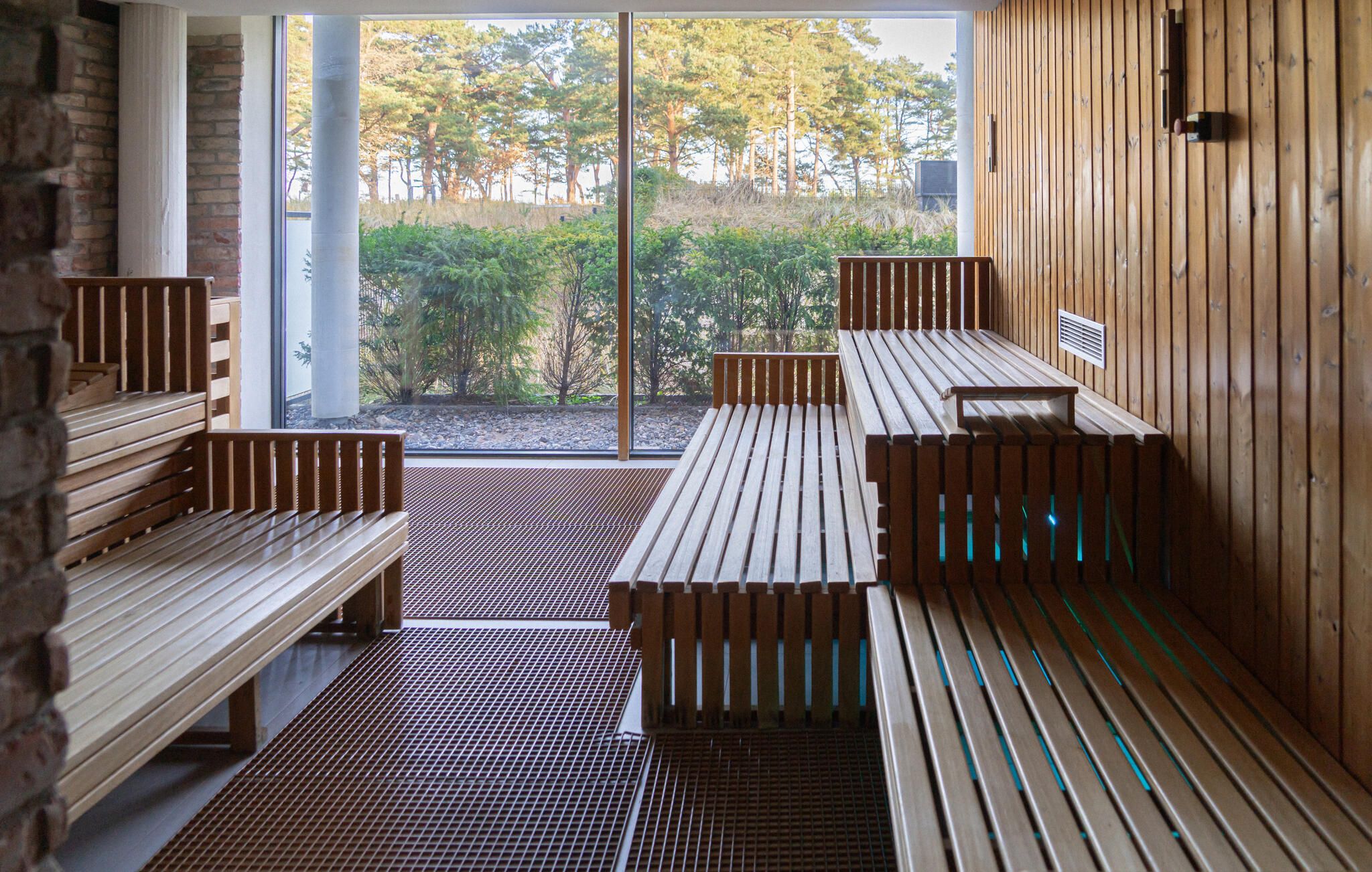 Sauna, jossa on puiset lauteet ja lasiovi, joka johtaa puutarhaan.