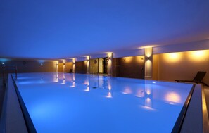 A large indoor swimming pool with a clear view of the pool area, a door leading to another room, and a chair by the pool. - Beach front apartment in Binz with WiFi (Prora/Rügen)