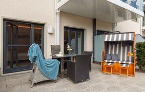 Un espace extérieur aménagé avec des meubles en osier, une table et un coin salon abrité.