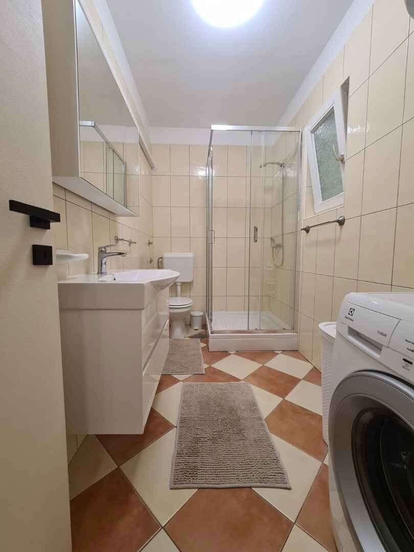Une salle de bain équipée d’une douche, de toilettes, d’un lavabo et d’un lave-linge.