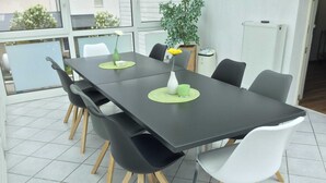 Een moderne eethoek met een rechthoekige tafel, zes stoelen en een potplant.