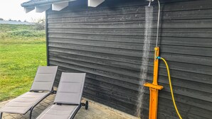 A wooden building with a water feature, two lounge chairs, and a yellow hose. - Beautiful home in Vejers Strand with sauna (Vejers Strand)