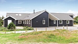 A two-story house with a dark exterior, a pitched roof, and a small porch area. - Beautiful home in Vejers Strand with sauna (Vejers Strand)