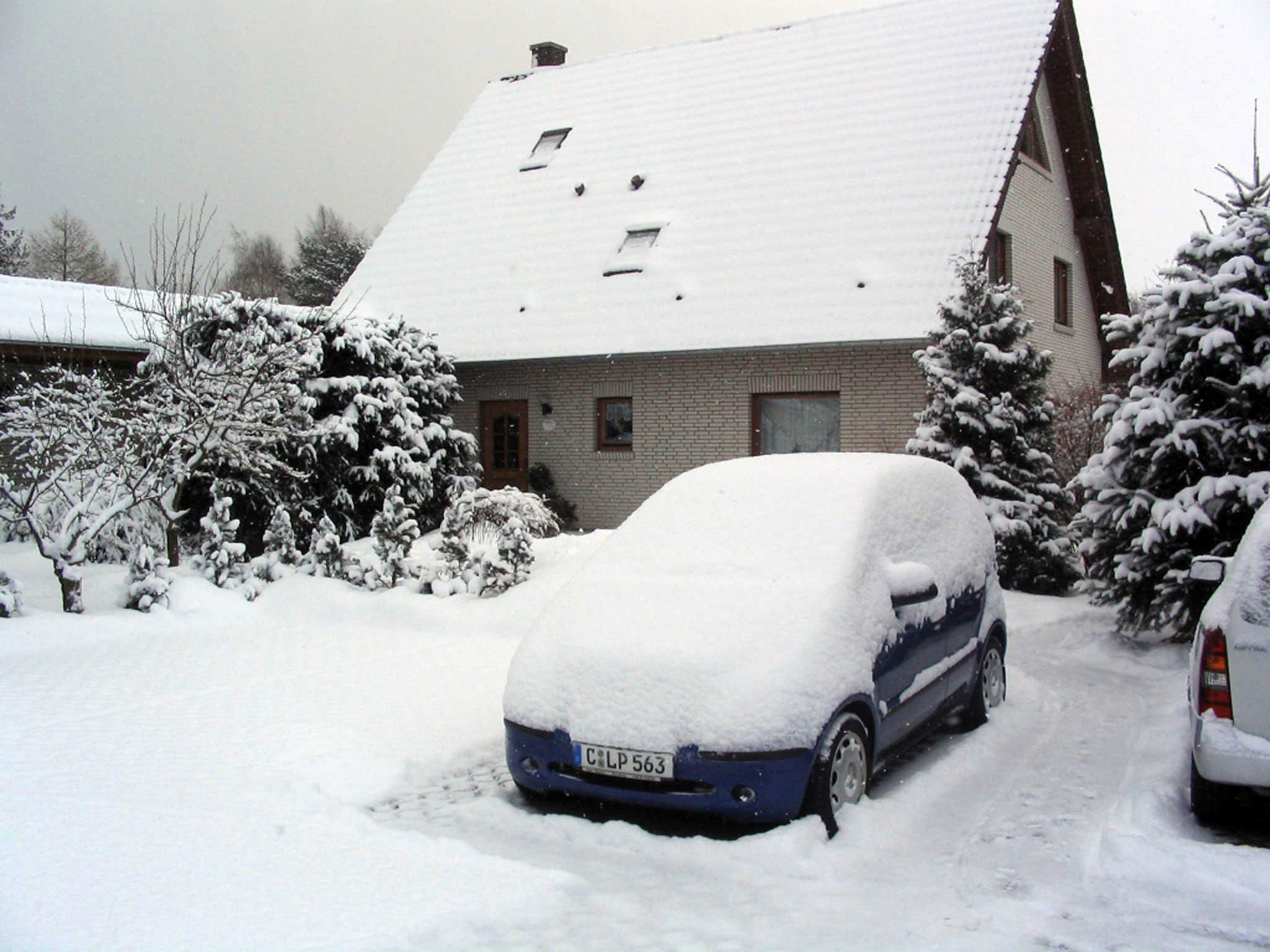 A residential building with a snow-covered roof and parked cars.
