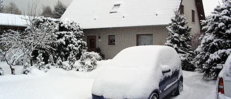 A residential building with a snow-covered roof and parked cars.