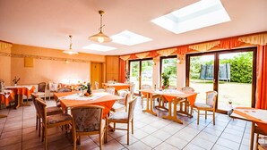 A dining area with tables and chairs, large windows, and a ceiling with skylights. - Vacation apartment 1 - Family-run guesthouse & vacation apartments Fischer-Haus (Trassenheide)